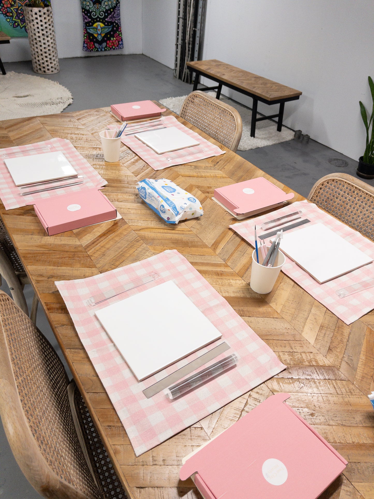 Wooden dining table set with pink placemats, and craft supplies.