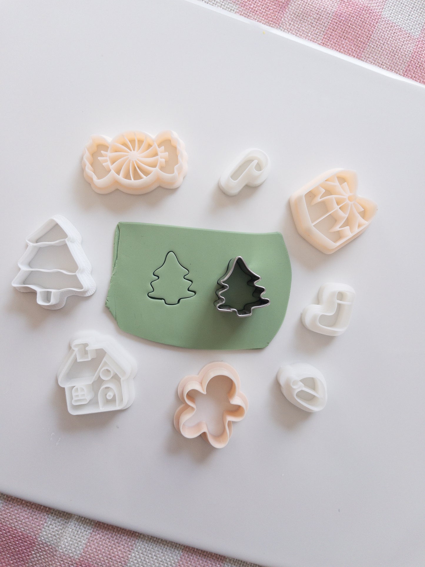 Set of Christmas-themed clay cutters on a white surface with a pink cloth underneath.