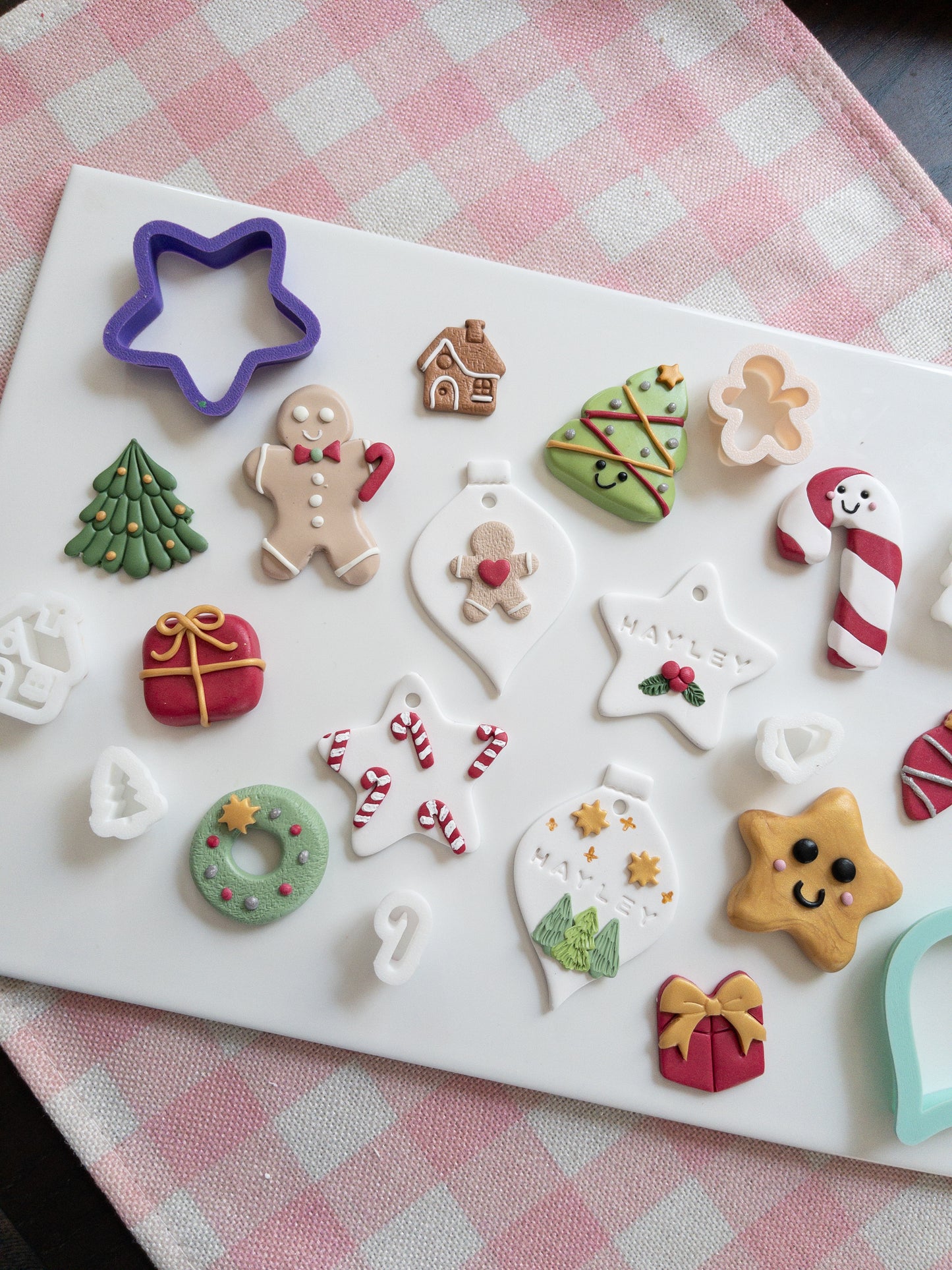 Set of Christmas-themed ornaments and magnets on a white tray with a checkered tablecloth background.