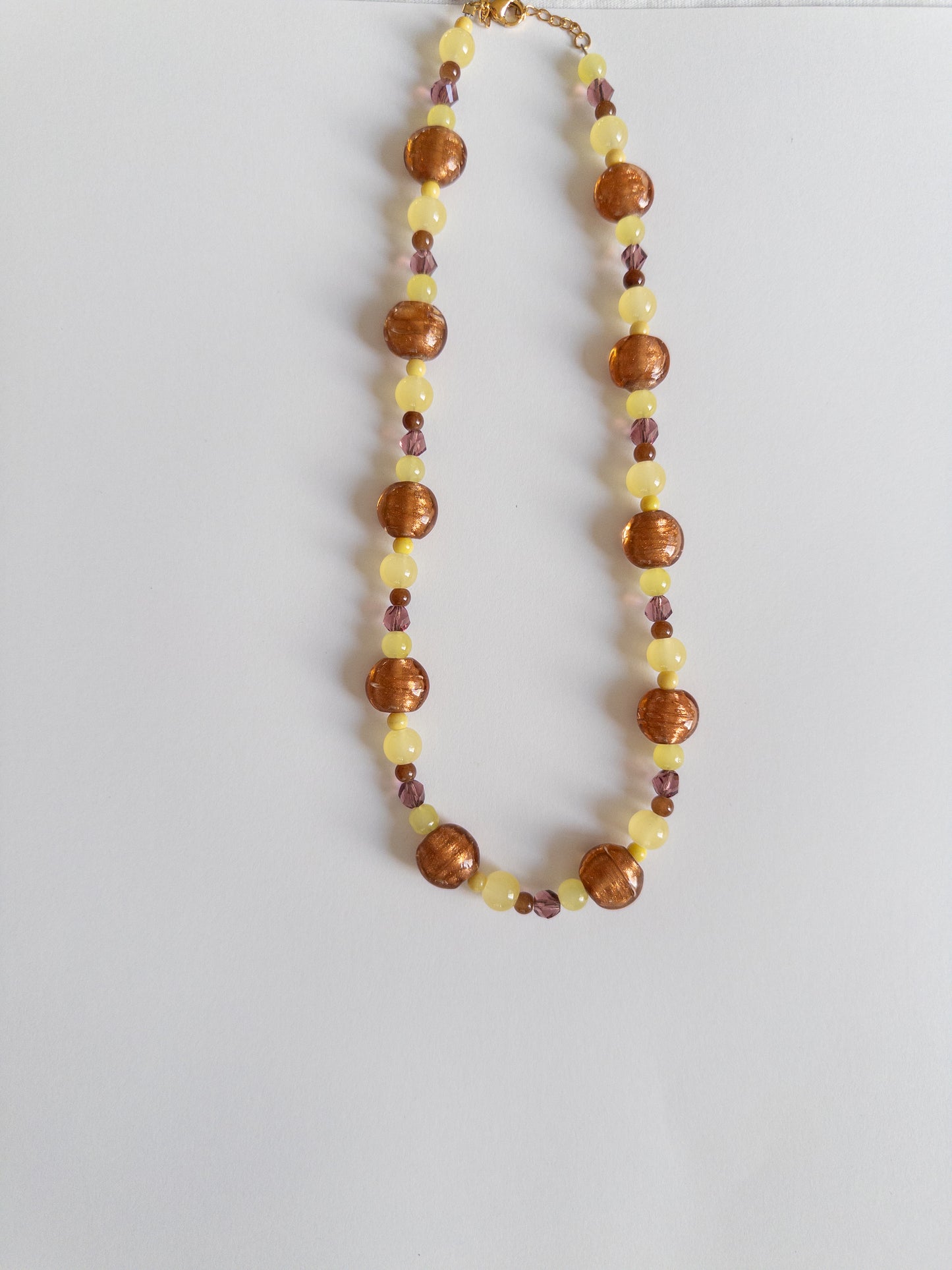 Yellow and brown chunky beaded necklace on white background
