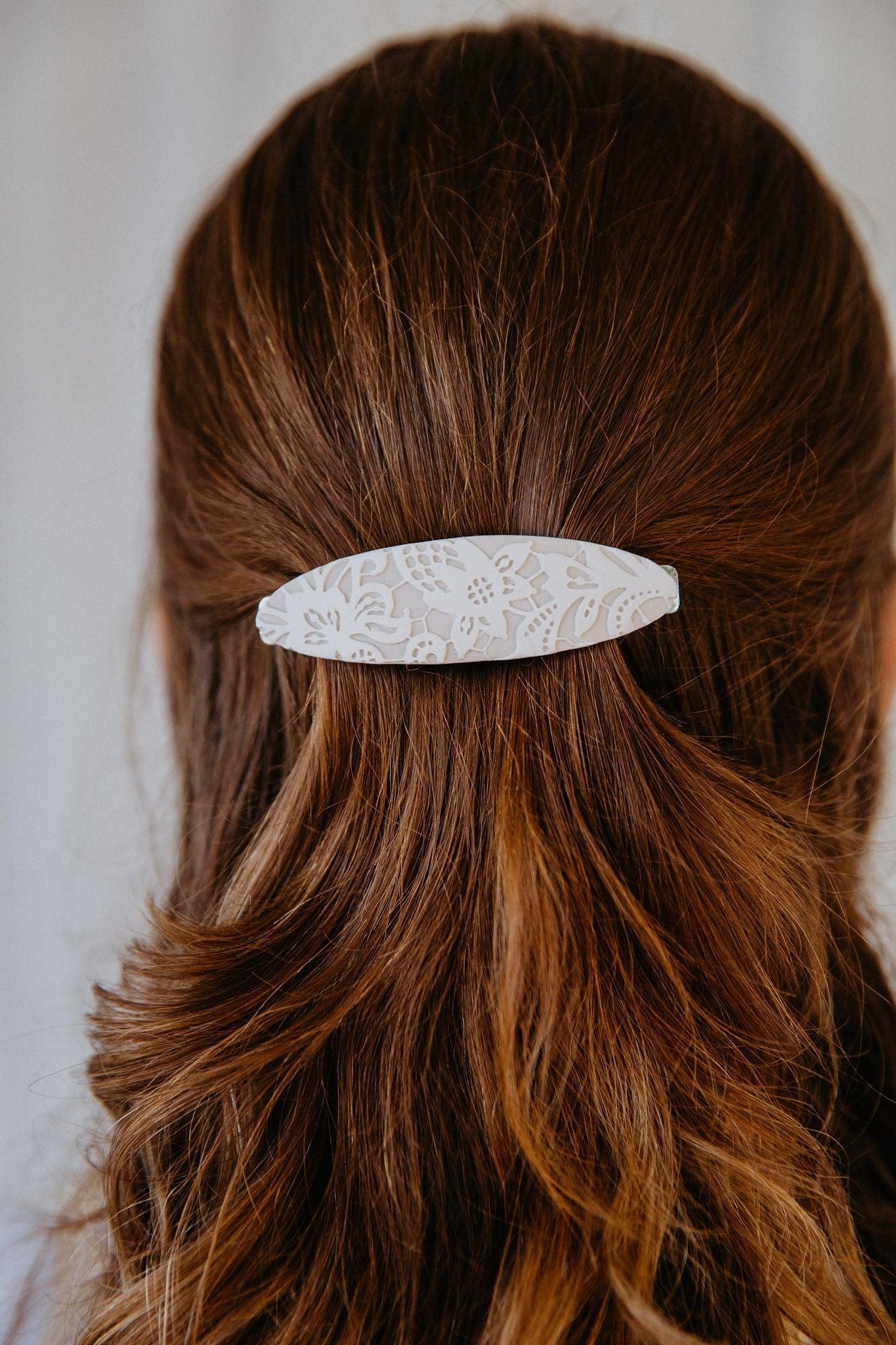 Cream lace hair barrette holding a models hair back in a half up/down hairstyle