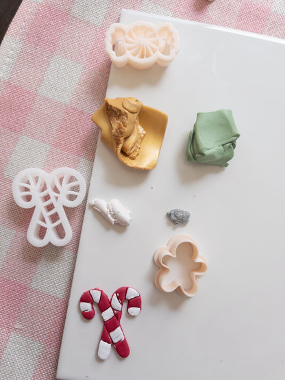 Set of colourful clay and  clay cutters on a white surface with a pink checkered fabric background.