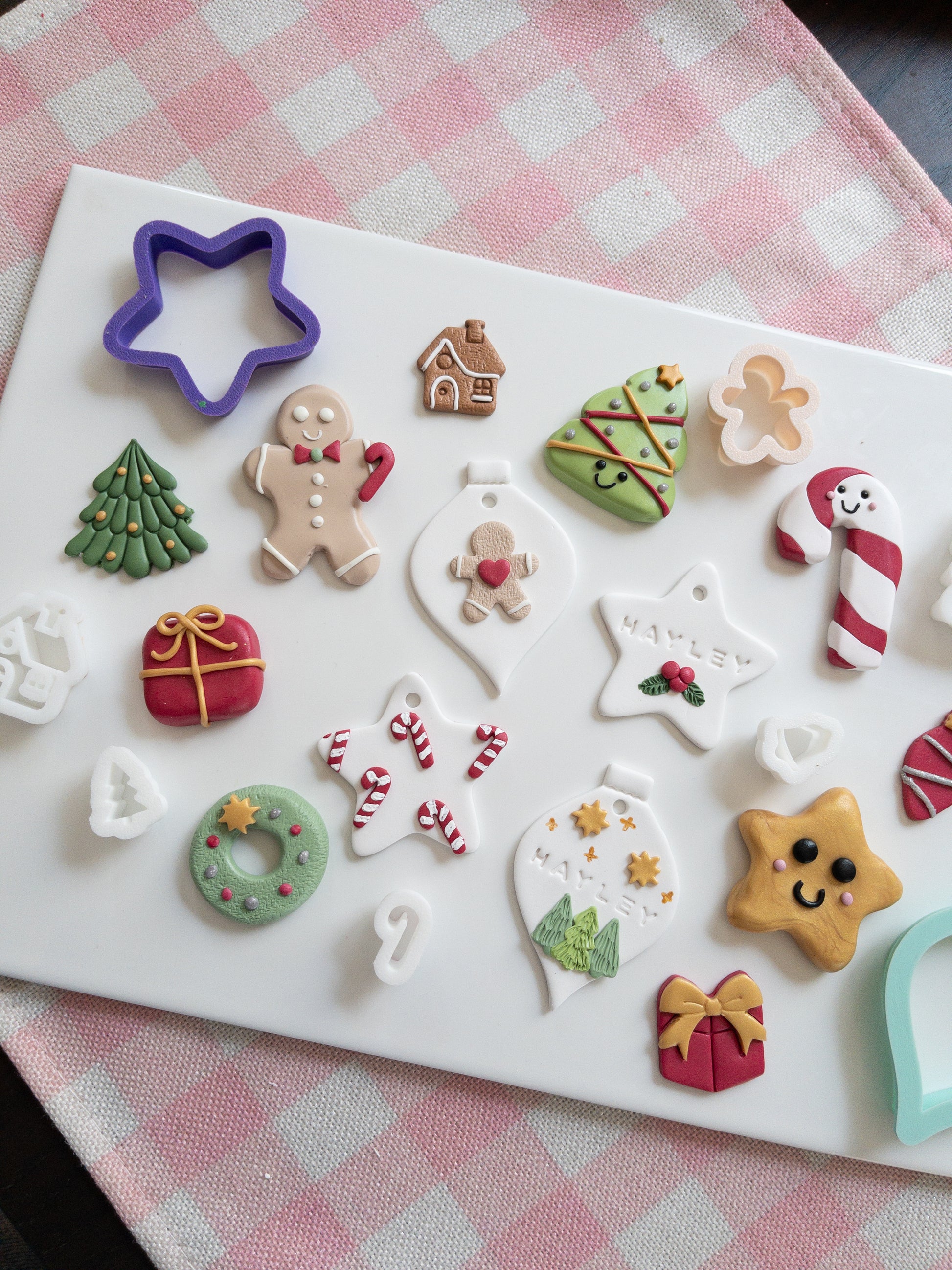 Set of Christmas-themed ornaments and magnets on a white tray with a checkered tablecloth background.