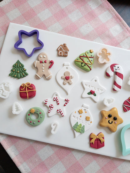 Set of Christmas-themed ornaments and magnets on a white tray with a checkered tablecloth background.