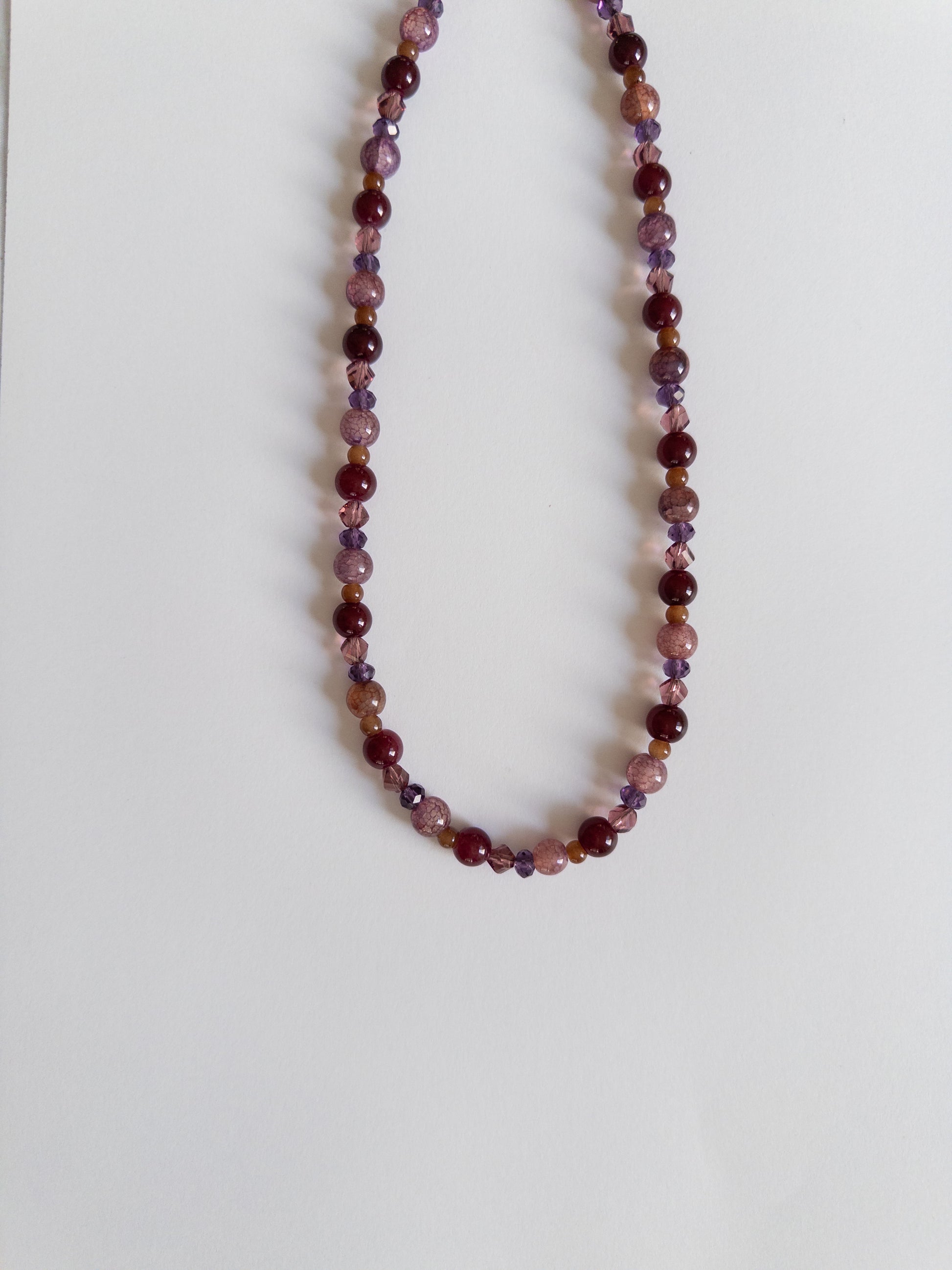 Acai berry coloured beaded necklace on white background