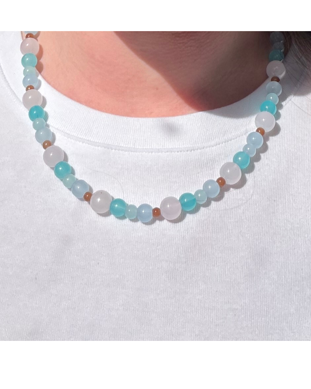 Sample of blue and brown beaded necklace on model wearing a white t-shirt