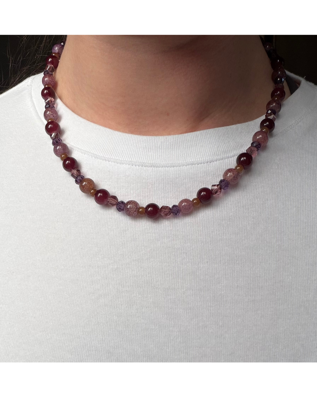 Close up on glass beaded necklace on a model wearing a white shirt.