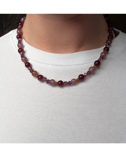Close up on glass beaded necklace on a model wearing a white shirt.