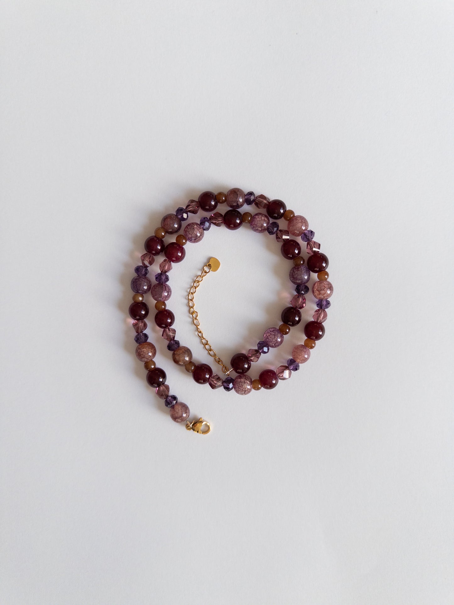 Acai berry coloured beaded necklace styled on white background