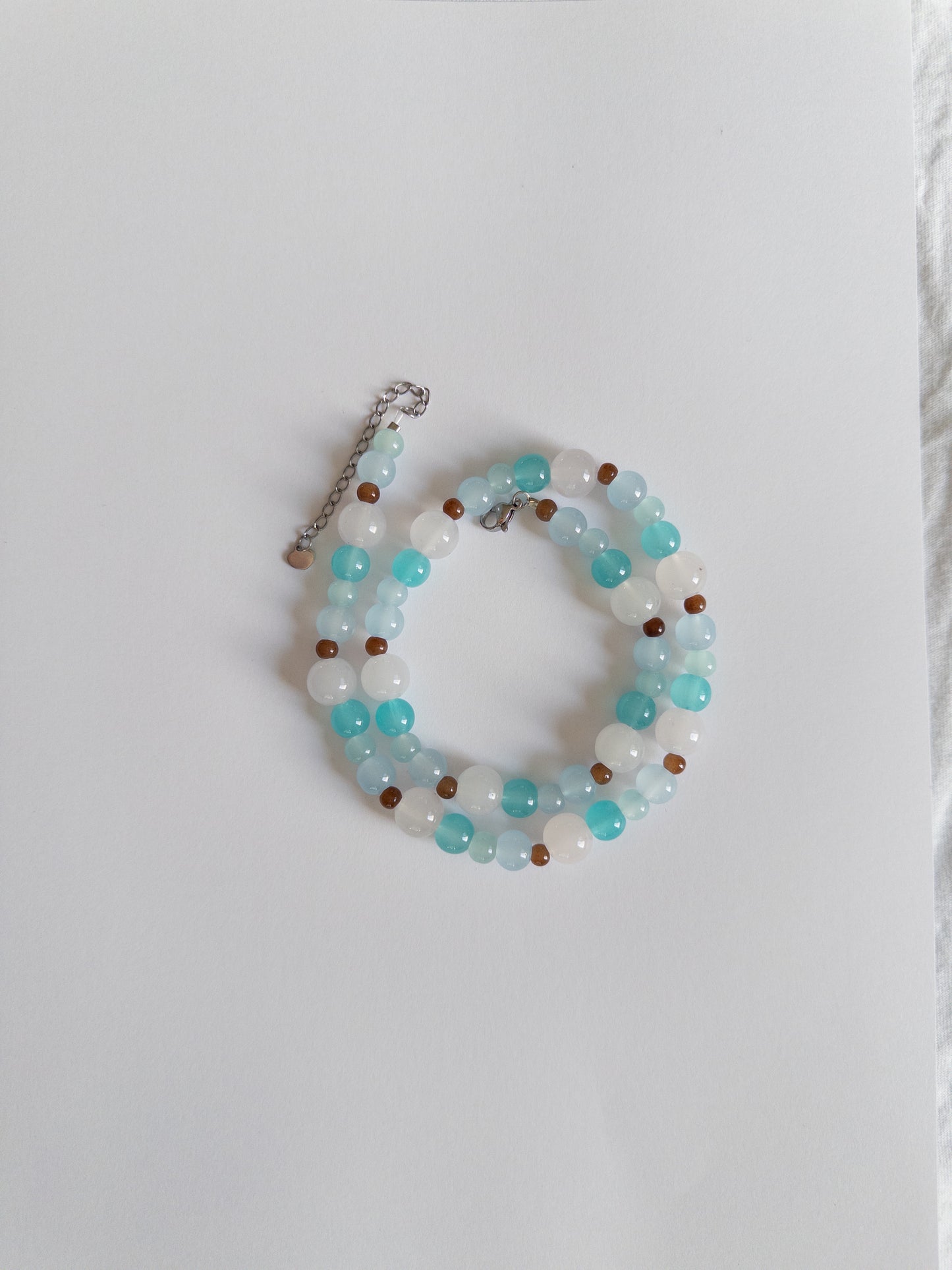 Blue and brown beaded necklace styled on white background