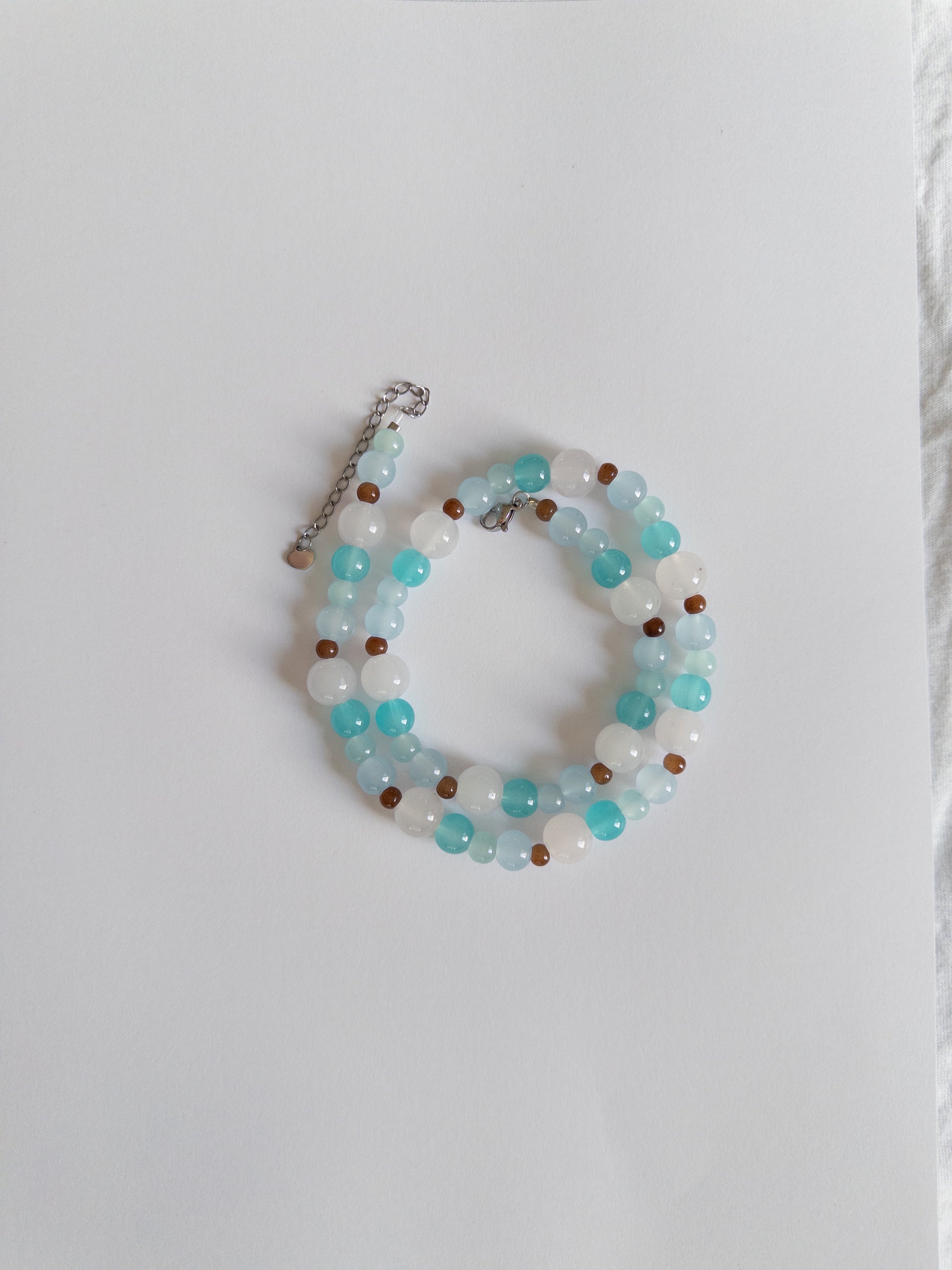 Blue and brown beaded necklace styled on white background