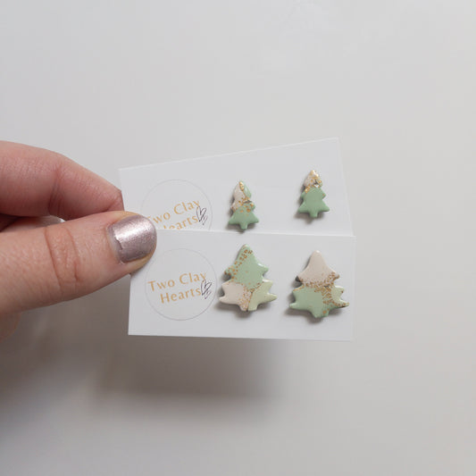 Hand holding a card with tree-shaped earrings on a white background