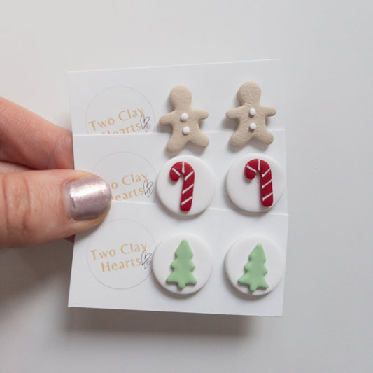 Set of Christmas-themed stud earrings on a card held by a hand.
