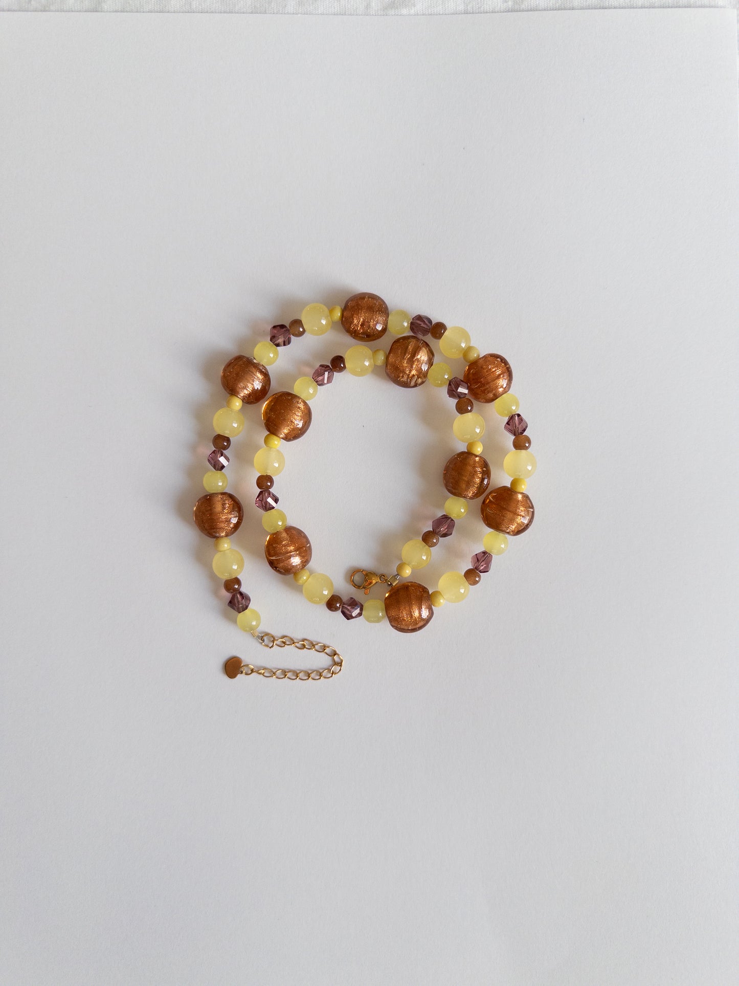 Yellow and brown chunky beaded necklace styled on white background
