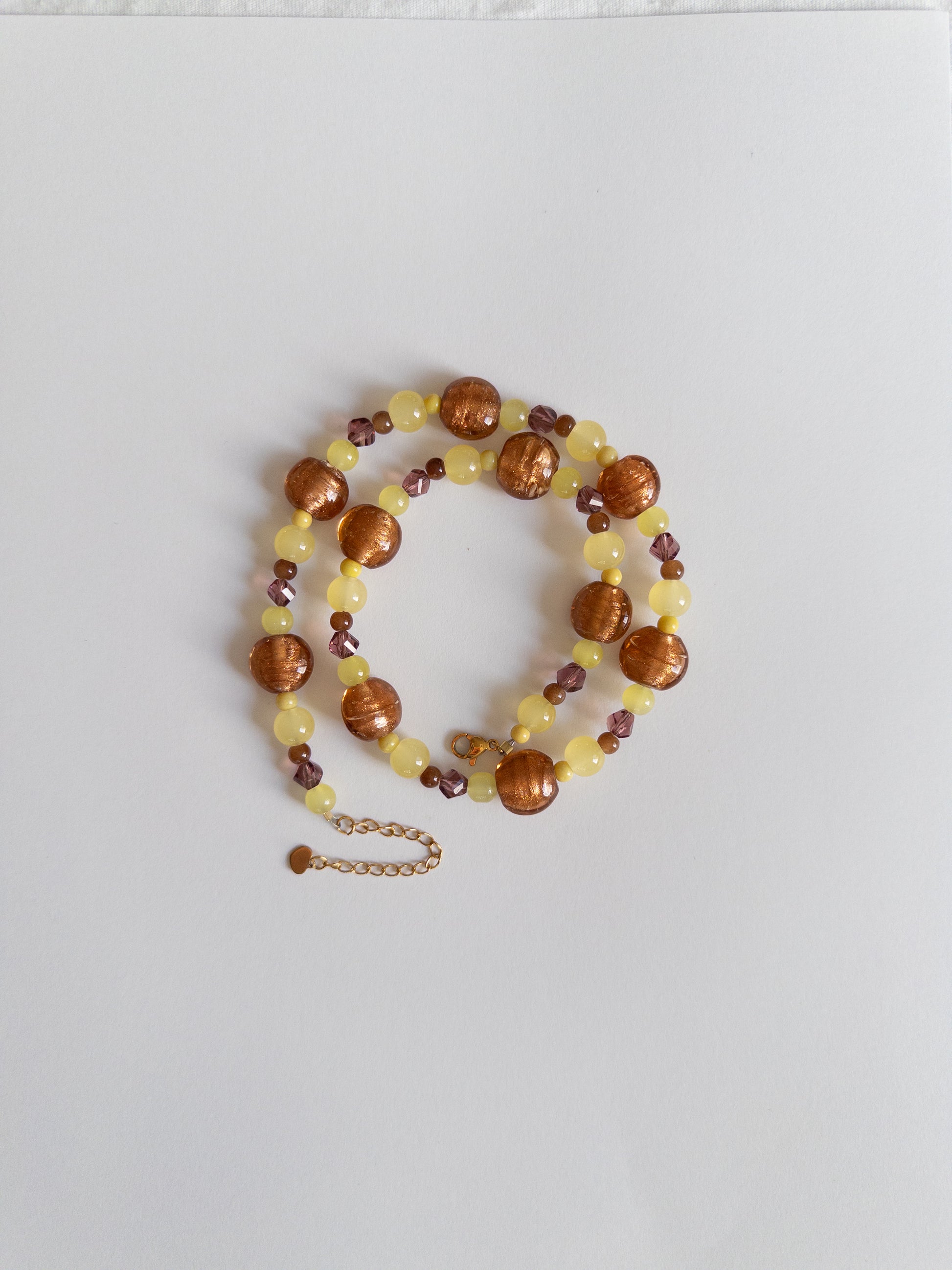 Yellow and brown chunky beaded necklace styled on white background