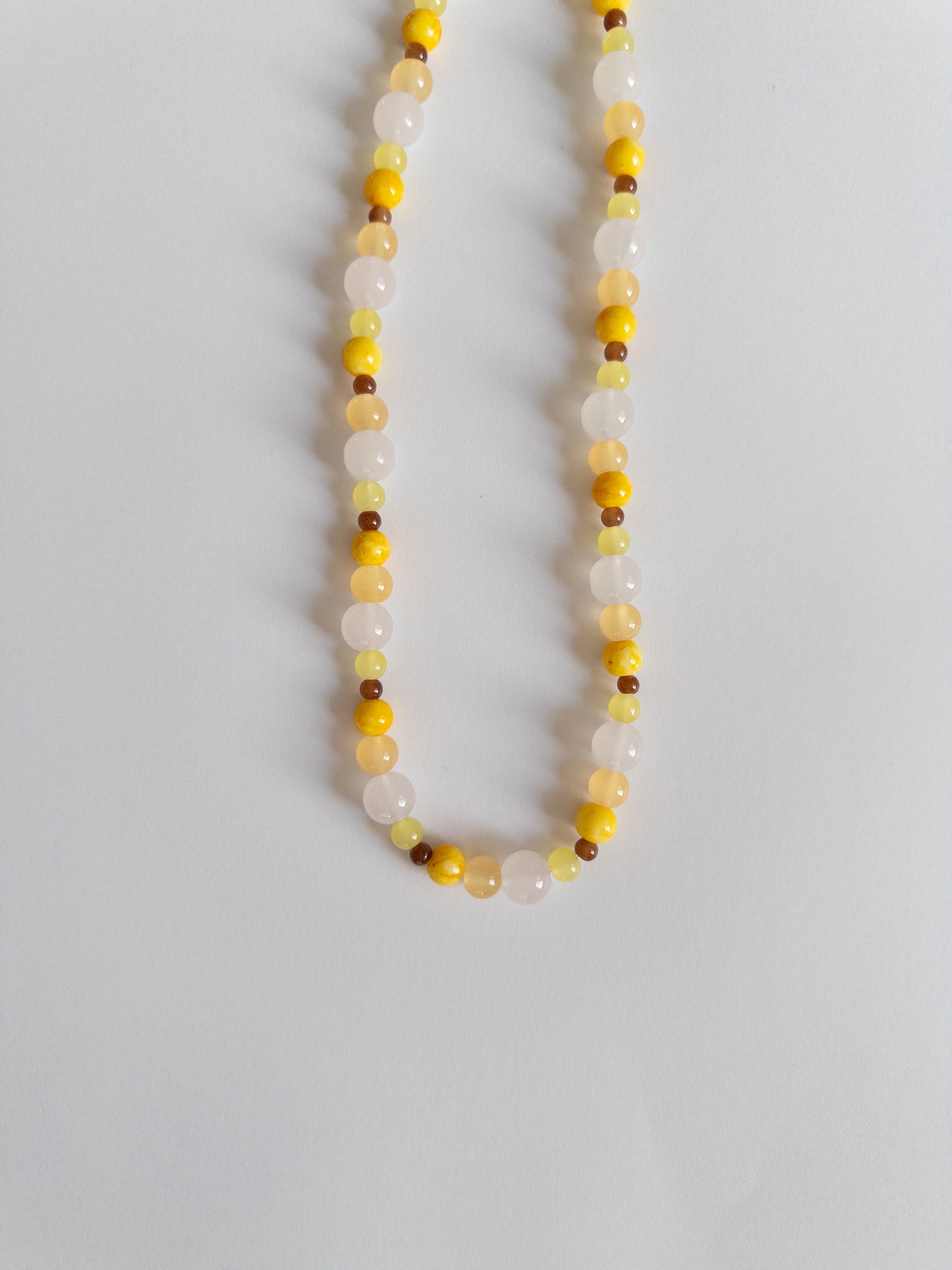 Yellow, brown and clear beaded necklace on white background