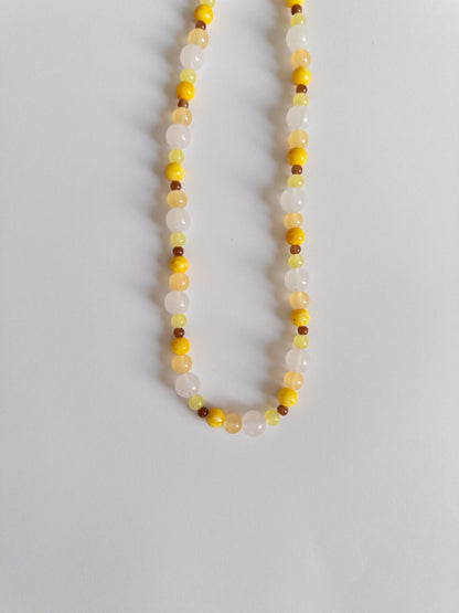 Yellow, brown and clear beaded necklace on white background