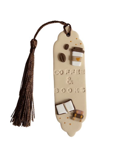 Beige polymer clay bookmark with brown tassel on white background. Bookmark features the words 'coffee & books' and decals of a coffee cup, coffee beans and books.