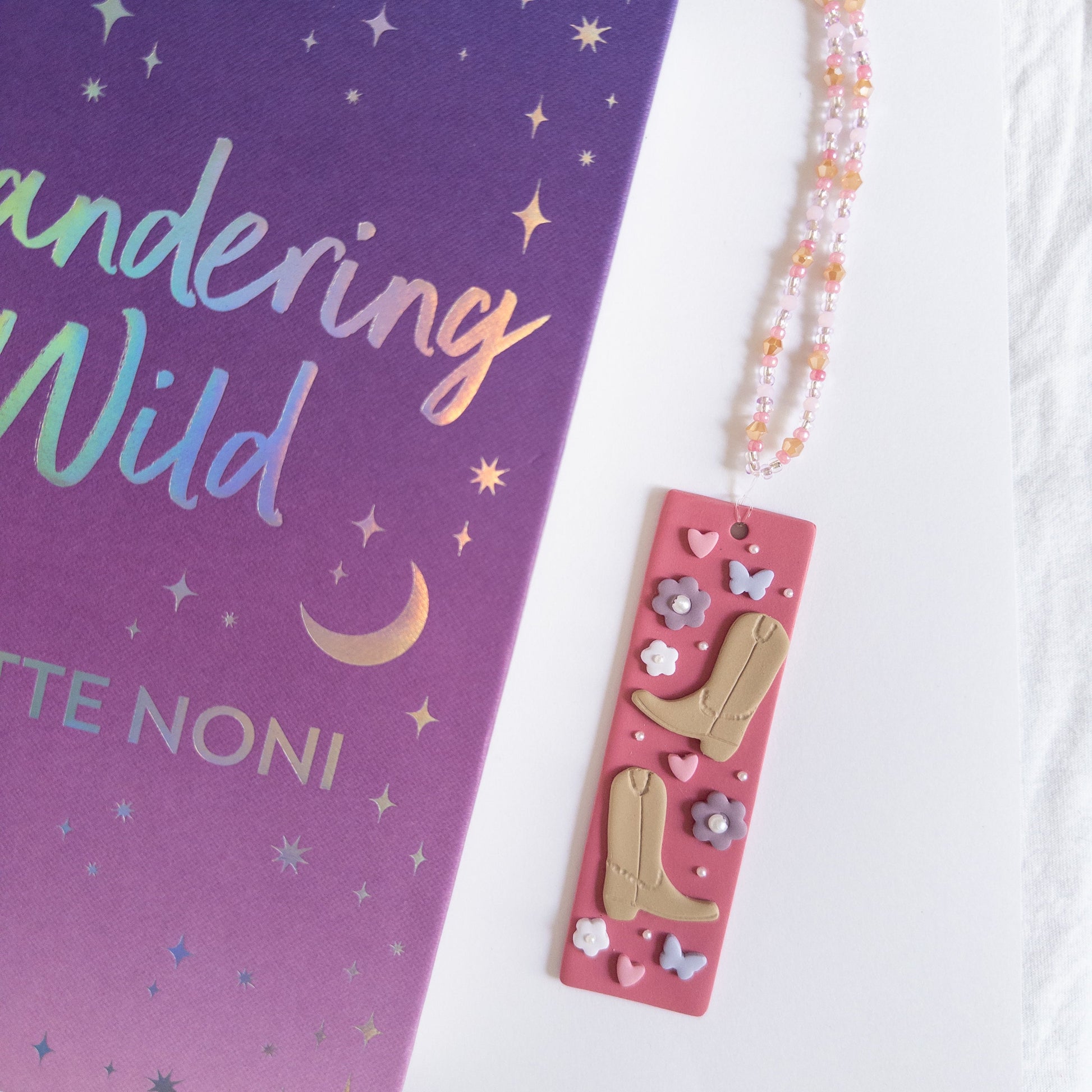 Cowboy polymer clay bookmark next to a book on a white background