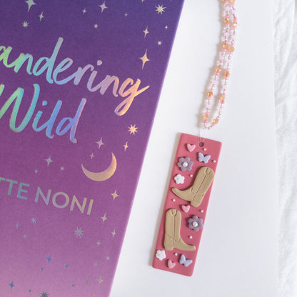 Cowboy polymer clay bookmark next to a book on a white background