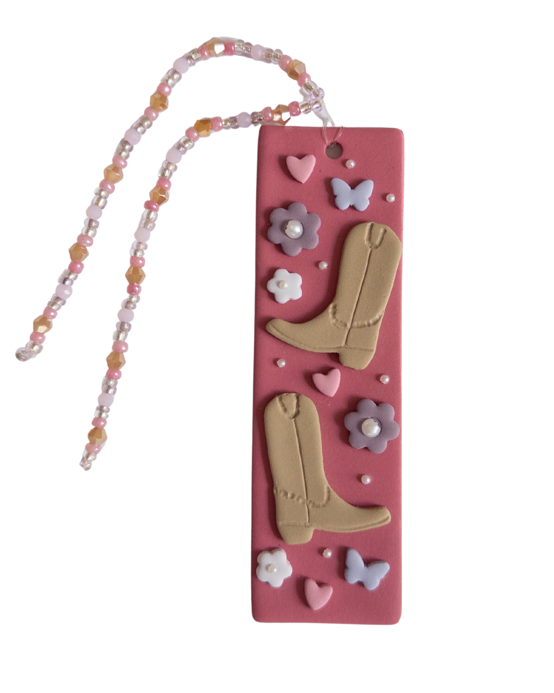 Polymer clay bookmark with a pink background and decorated with brown cowboy boots, purple flowers and butterflies and pink hearts and a matching beaded tassel