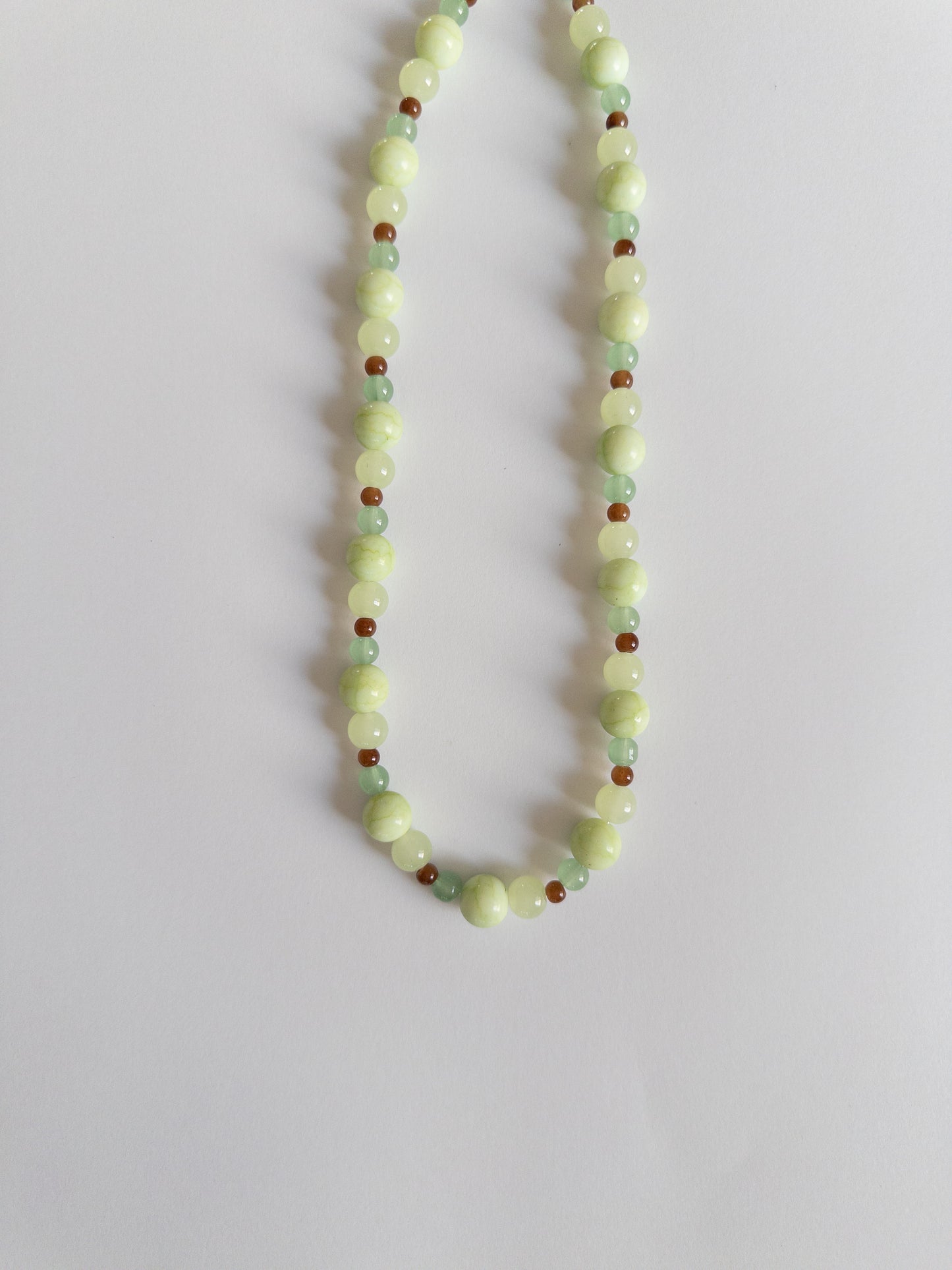 Green and brown beaded necklace on a white background