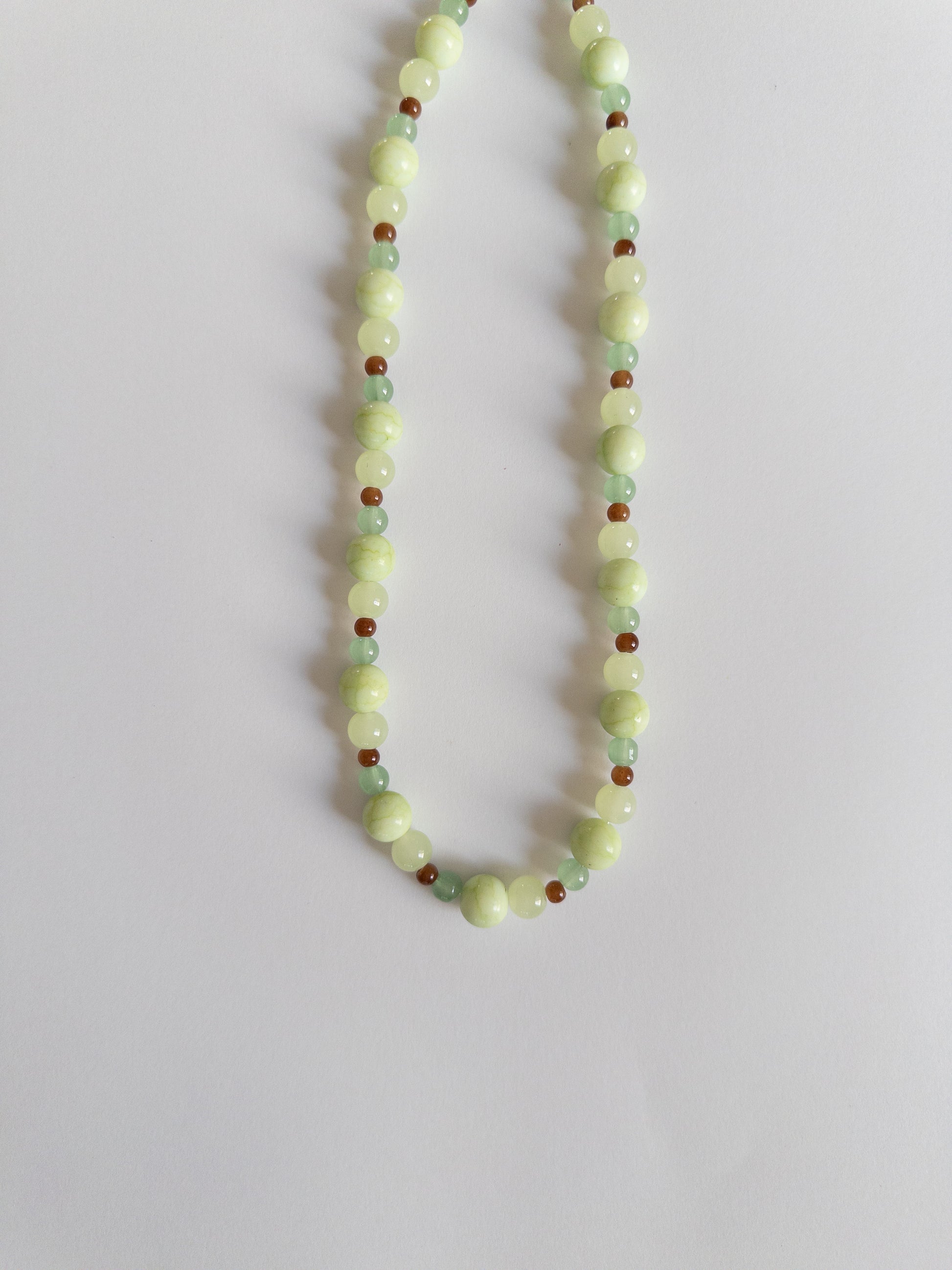 Green and brown beaded necklace on a white background