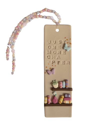 Bookmark with a bookshelf design, and the words 'just one more chapter', with matching beaded tassel on a white background