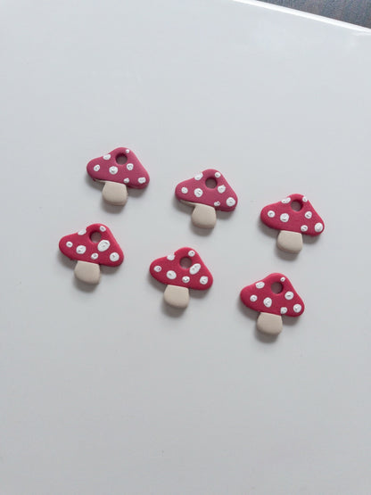 Five pink mushroom-shaped charms with white spots on a light gray background