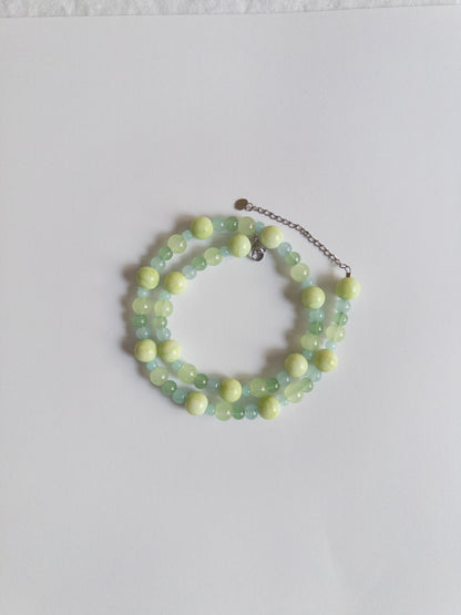 Green coloured glass bead necklace styled on white background