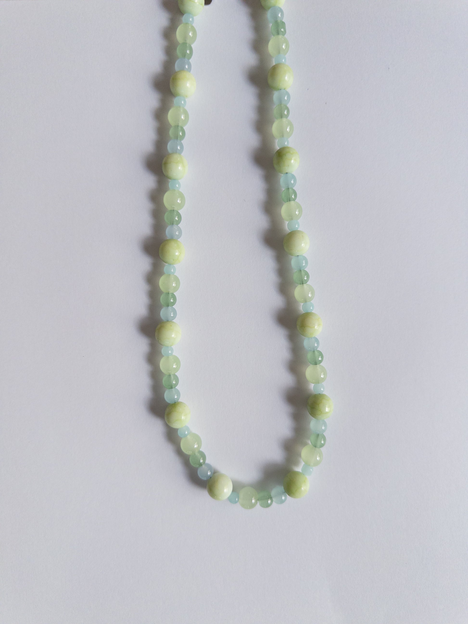 Green coloured glass bead necklace on white background