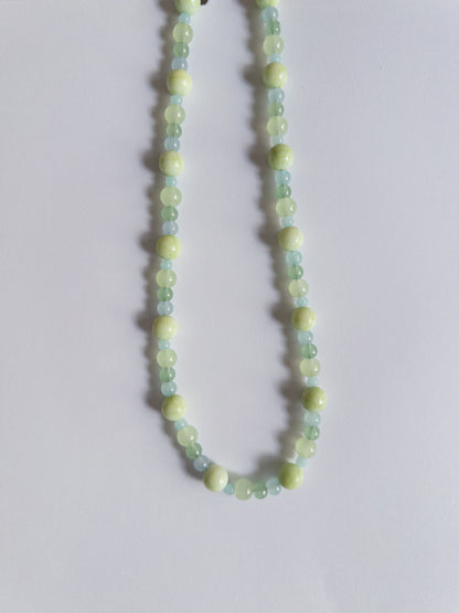 Green coloured glass bead necklace on white background