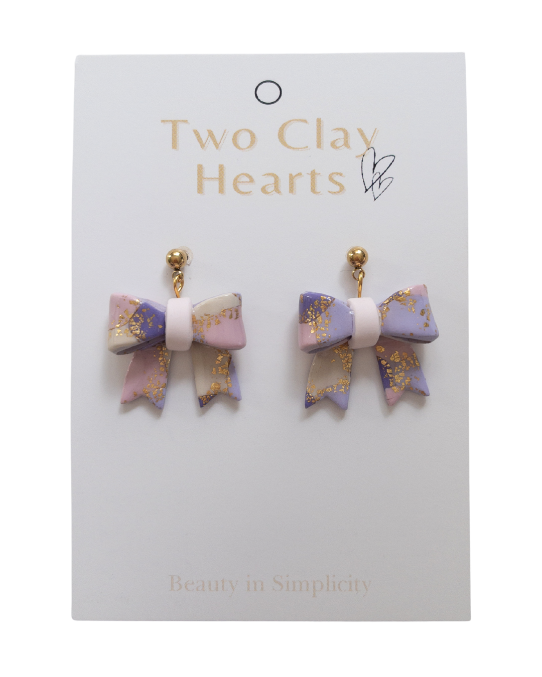 Pair of bow-shaped earrings on a 'Two Clay Hearts' branded card.