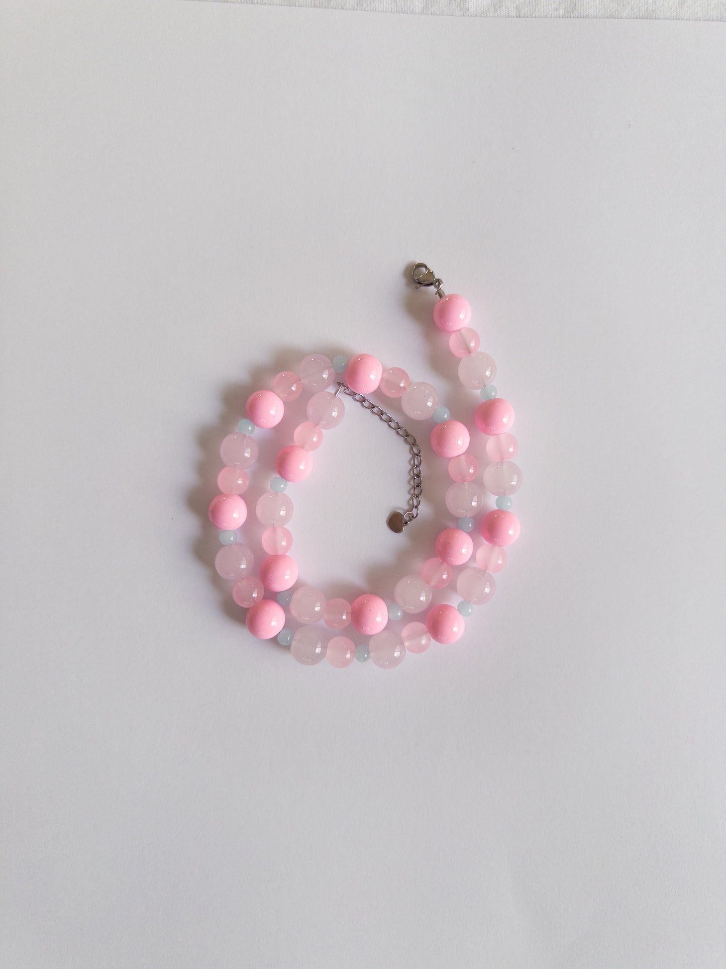 Pink and blue beaded necklace styled on white background