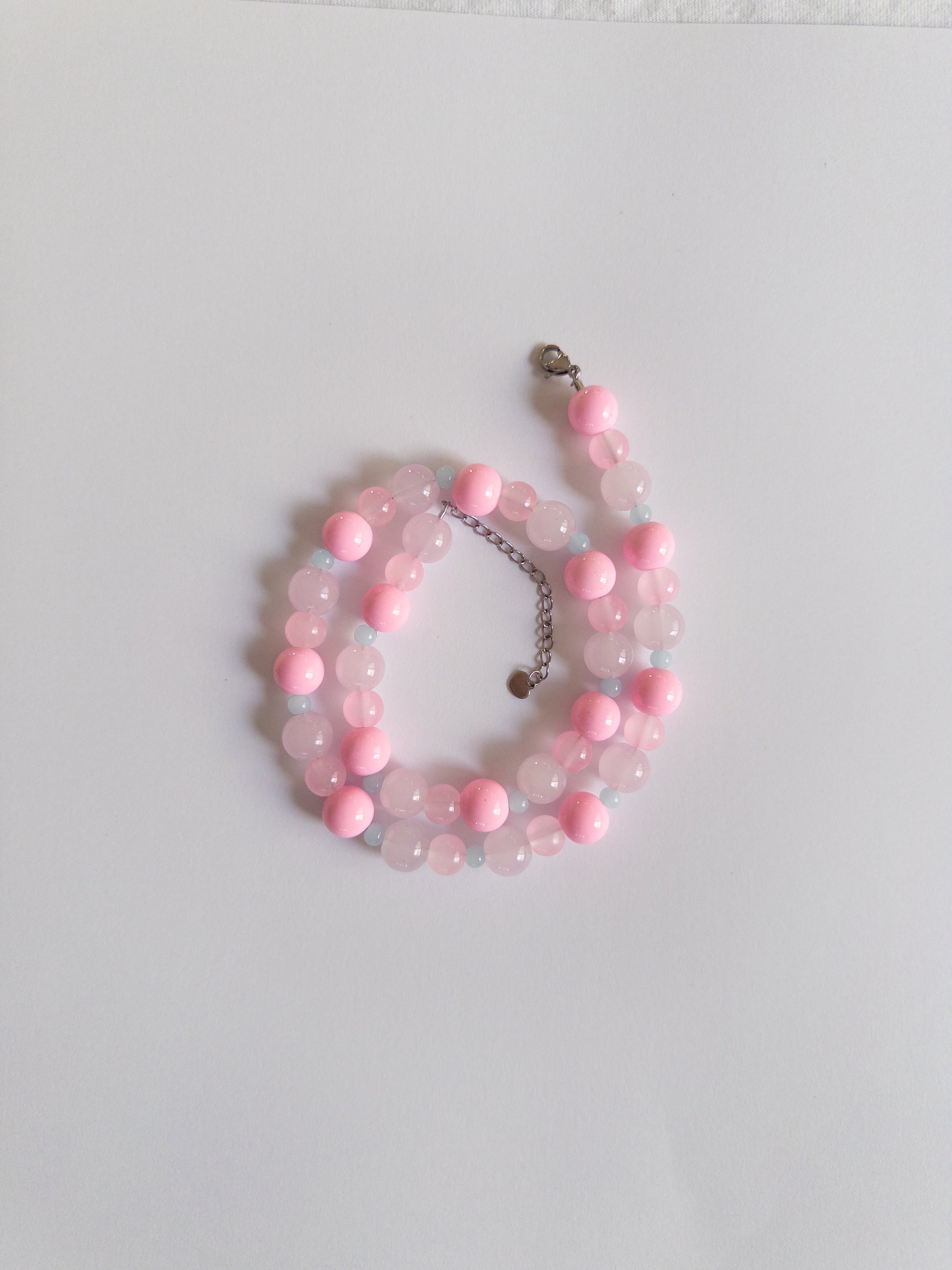 Pink and blue beaded necklace styled on white background