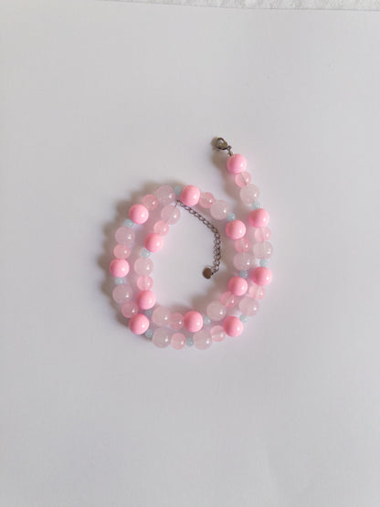 Pink and blue beaded necklace styled on white background