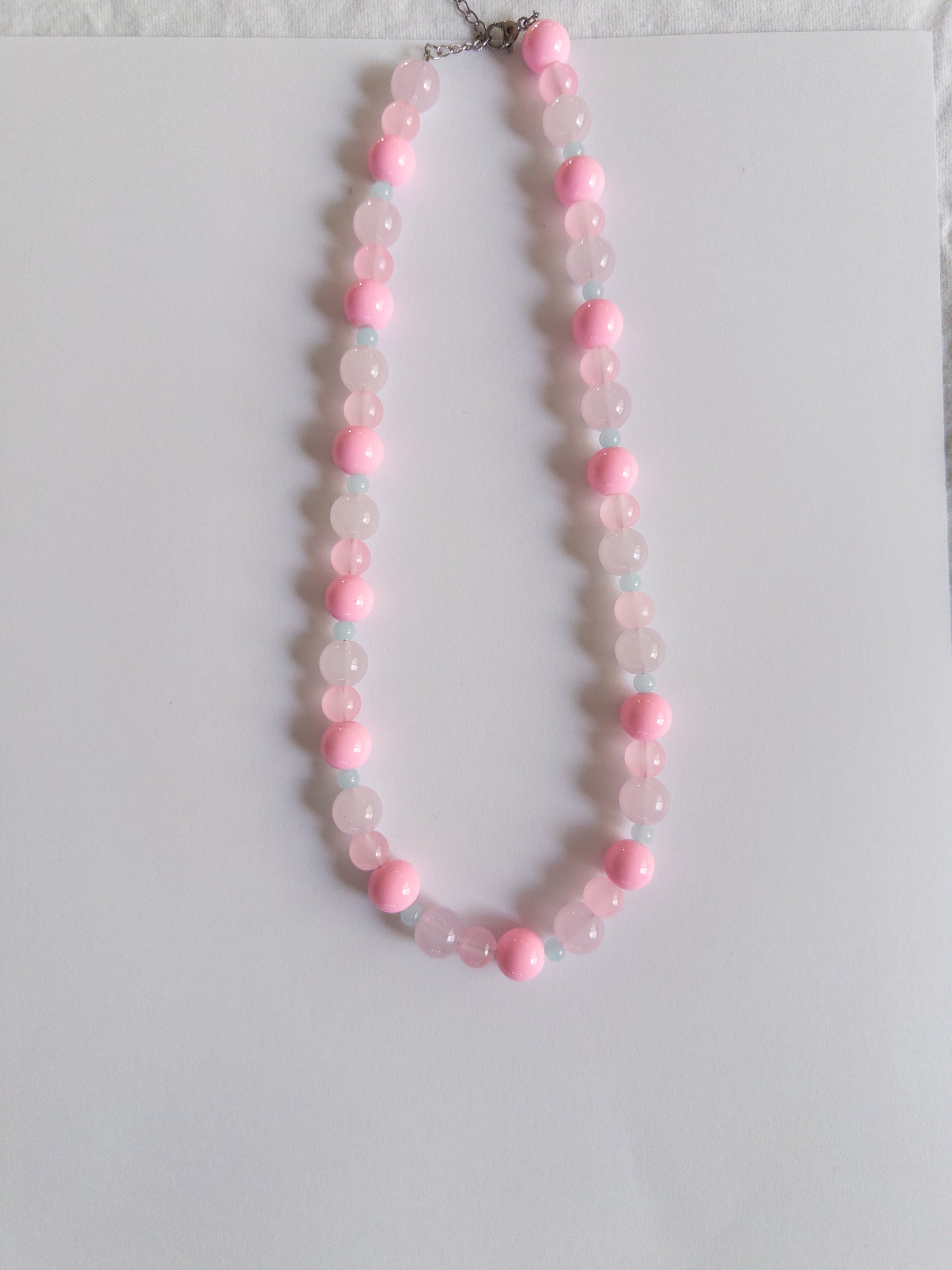 Pink and blue beaded necklace on white background
