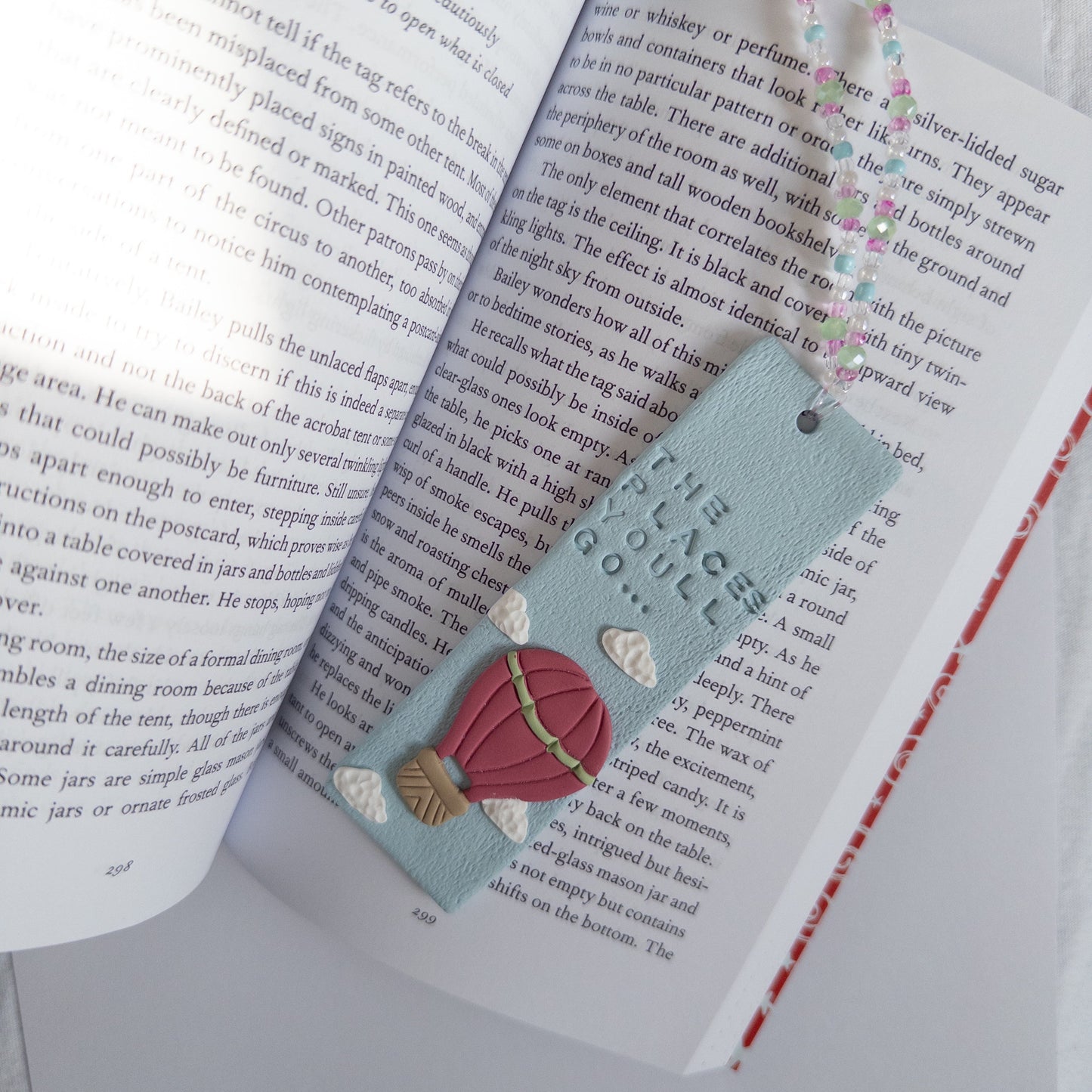 Blue polymer clay bookmark with design, on an open book page.
