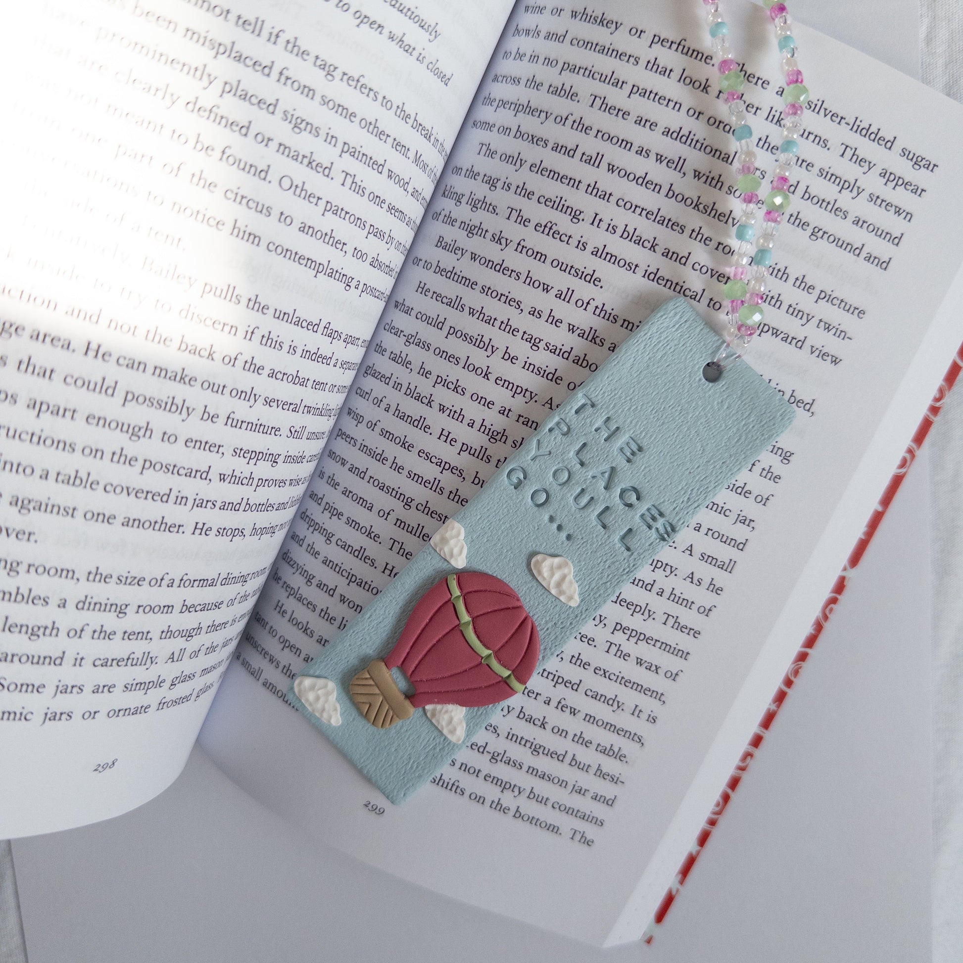 Blue polymer clay bookmark with design, on an open book page.