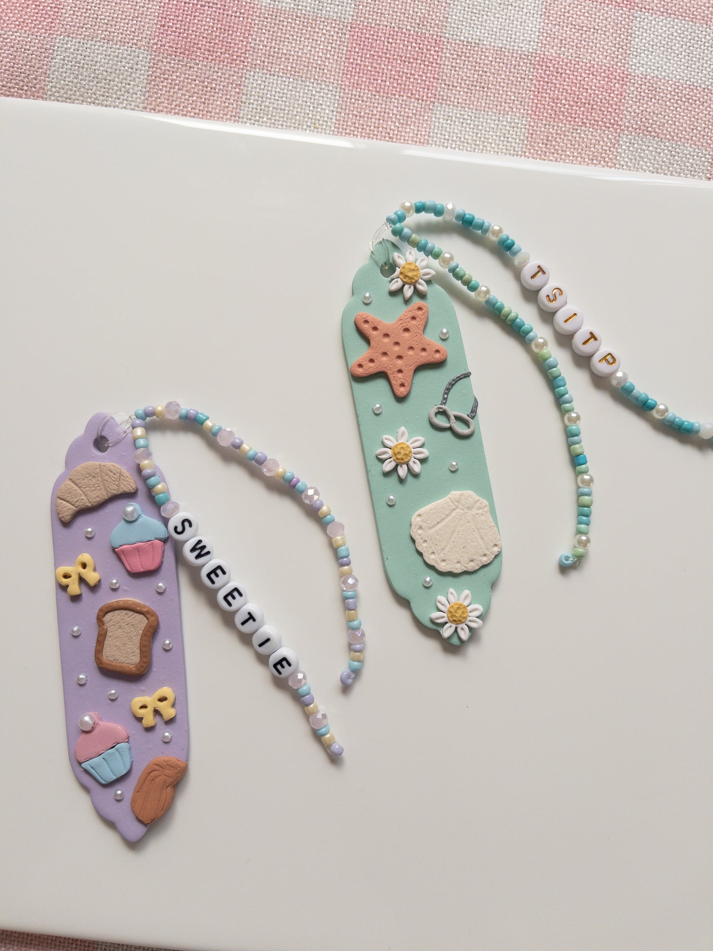 Two decorative bookmarks with beads and charms on a white surface.