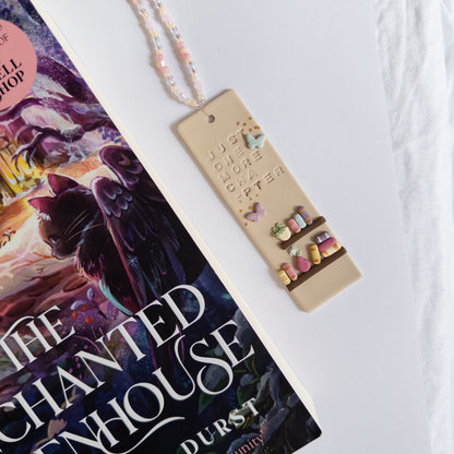 Polymer clay bookmark with beaded tassel next to reading book on white background