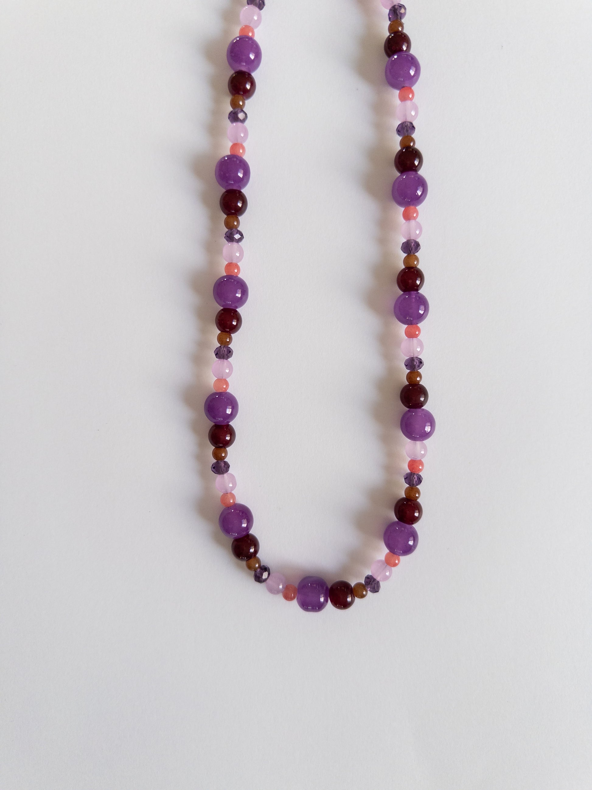 Dark purple glass bead necklace on white background