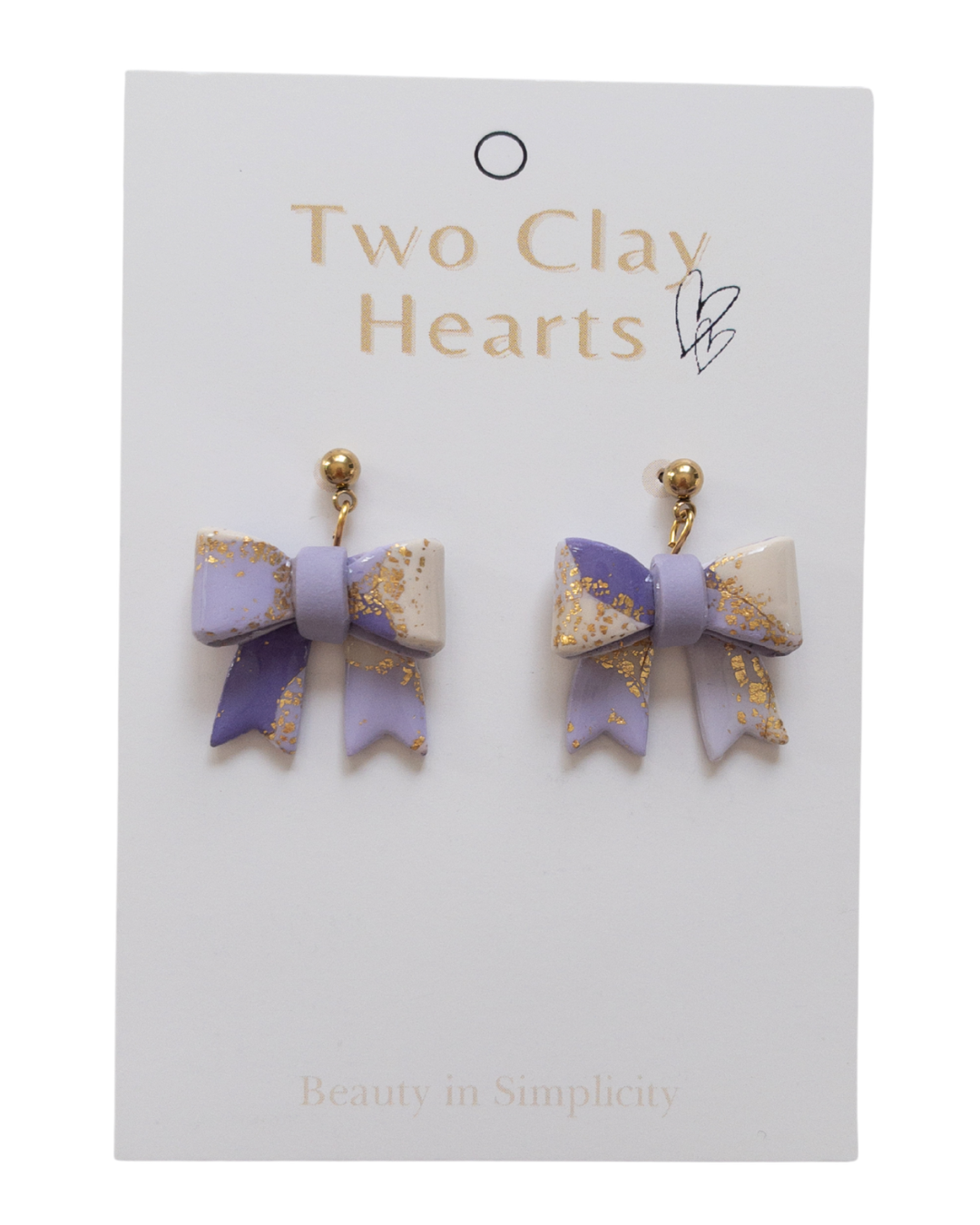 Pair of bow-shaped earrings on a 'Two Clay Hearts' branded card.