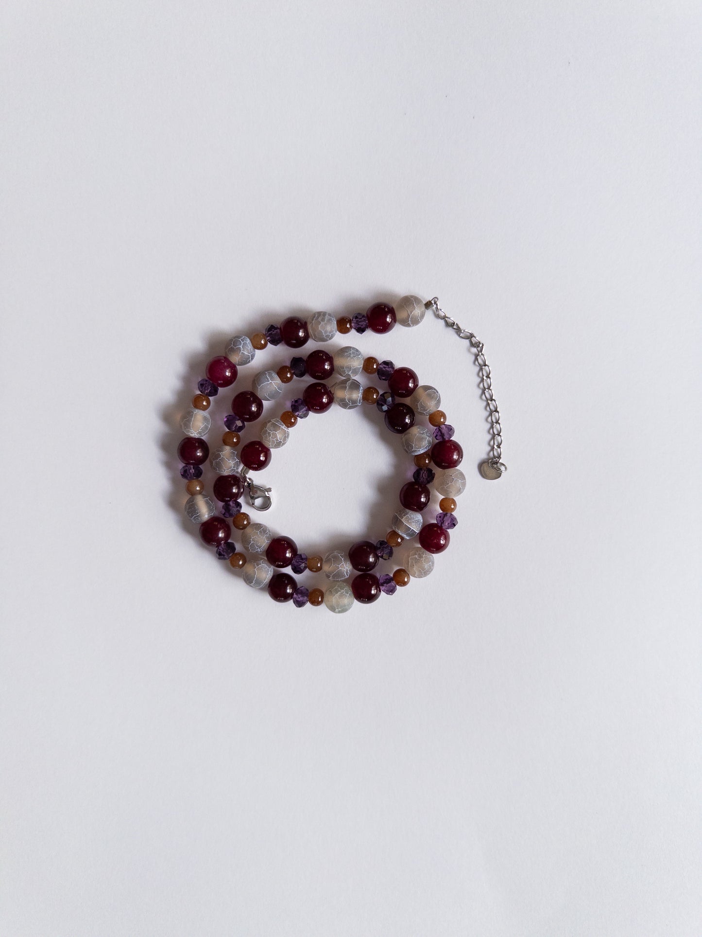 dark purple and magenta beaded necklace styled on white background