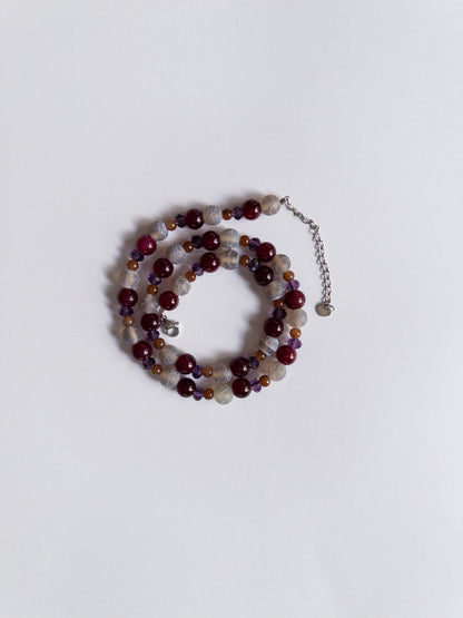 dark purple and magenta beaded necklace styled on white background
