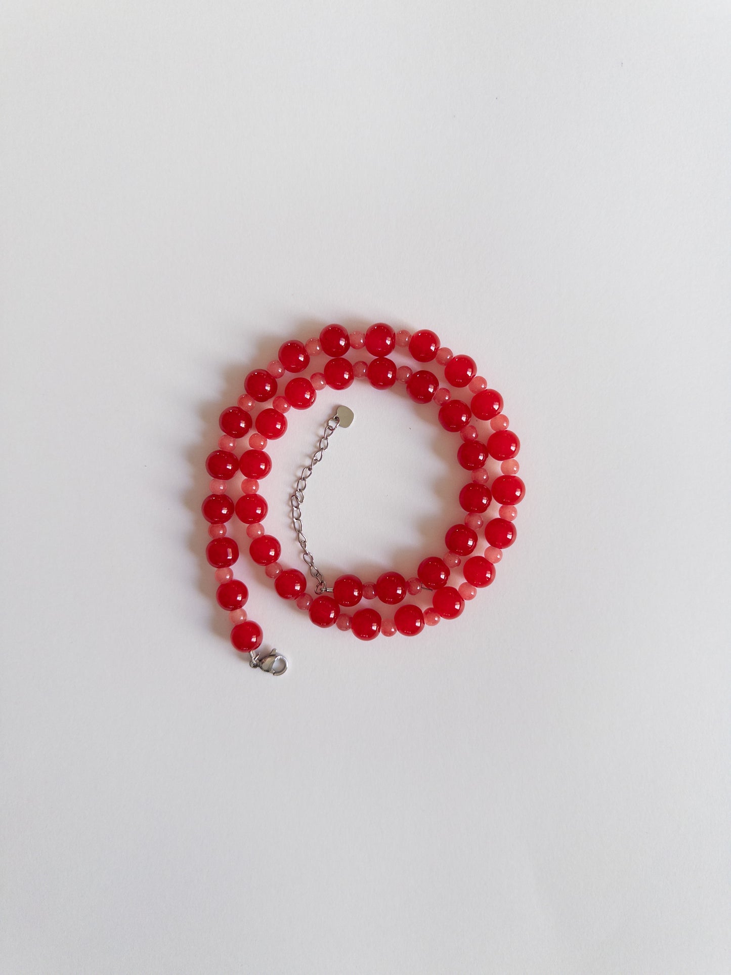 Glass beaded necklace in red tones styled on a white background