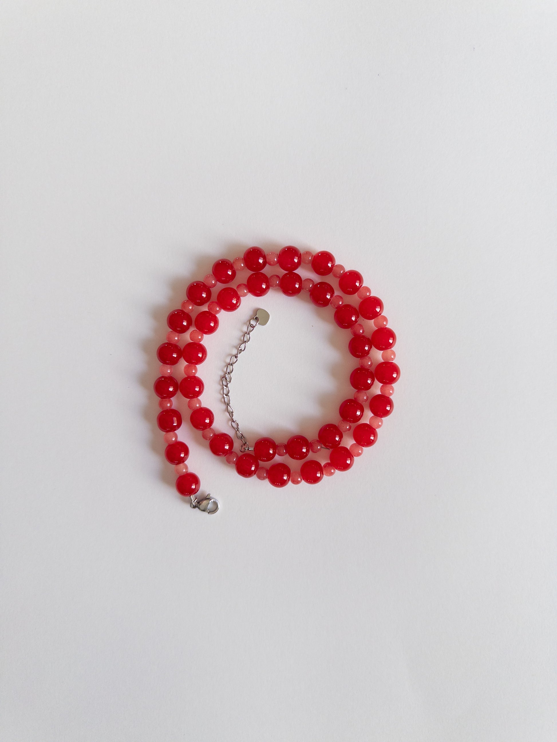 Glass beaded necklace in red tones styled on a white background