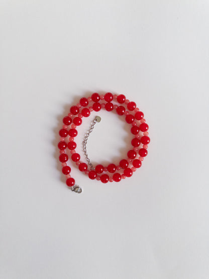 Glass beaded necklace in red tones styled on a white background