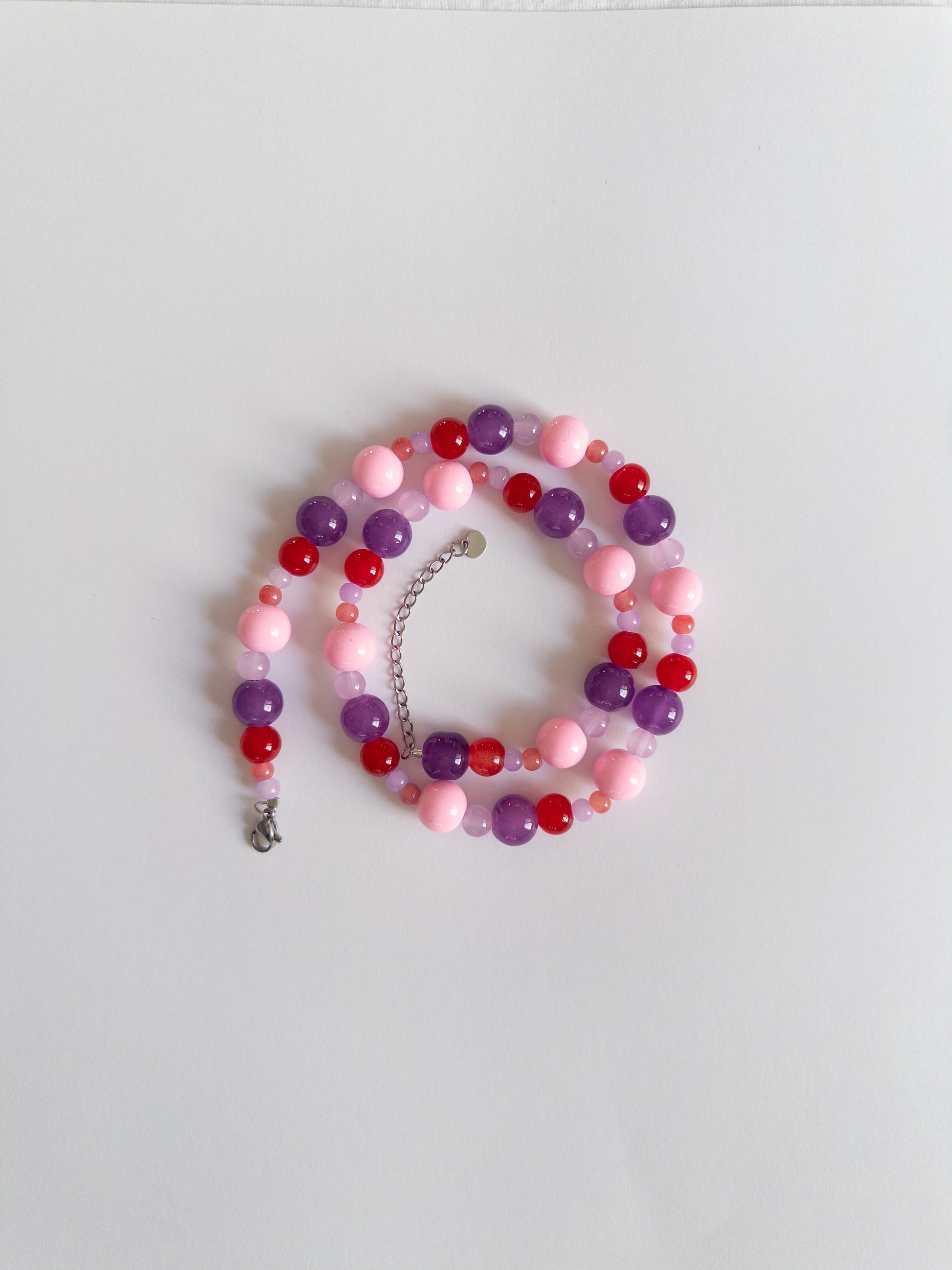 Berry coloured beaded necklace styled on white background