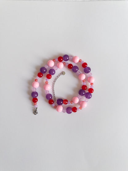 Berry coloured beaded necklace styled on white background